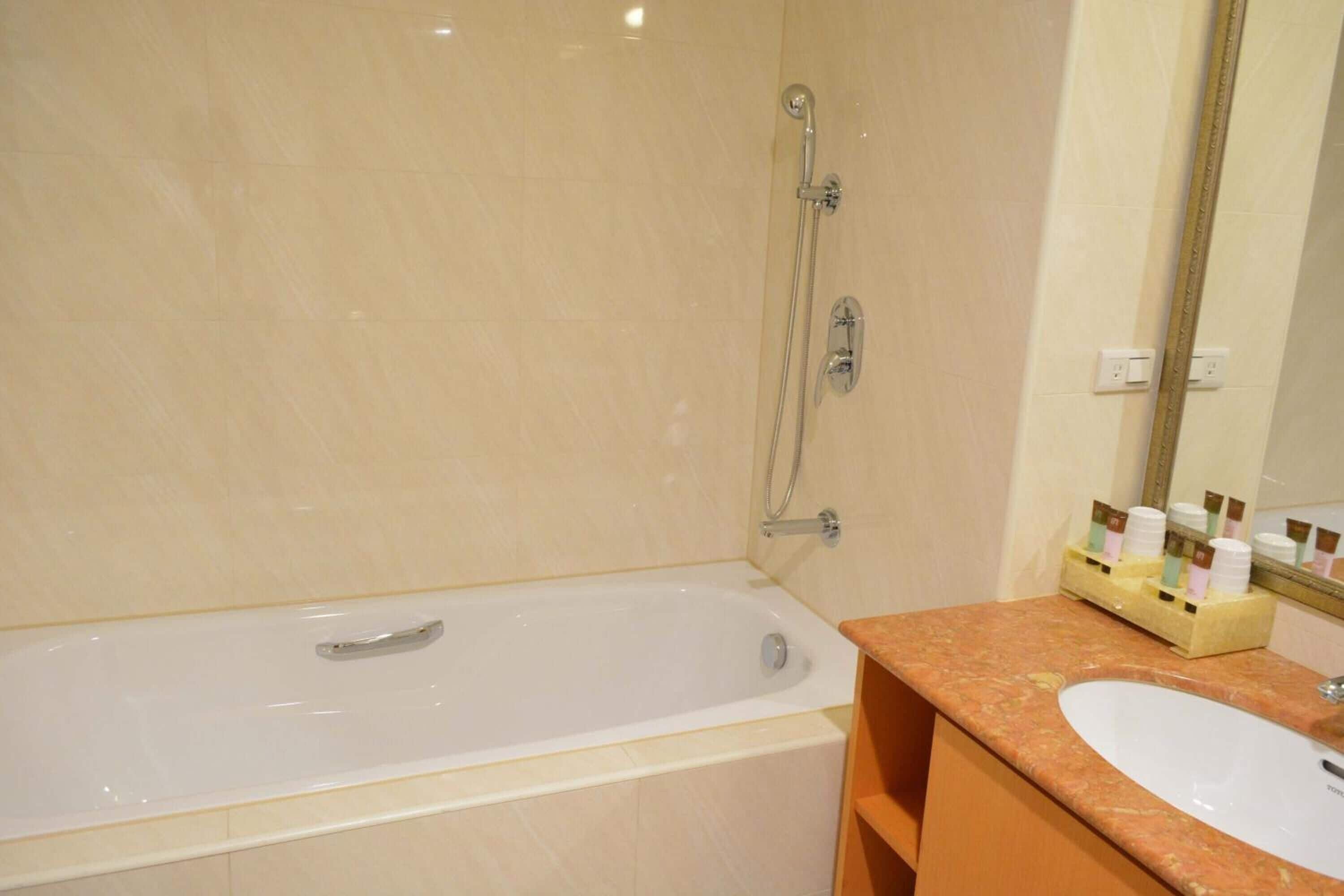 A bathroom with a bathtub, a sink, and a mirror.