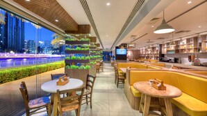 A modern restaurant with wooden furniture, a view of the cityscape, and a counter with various items.