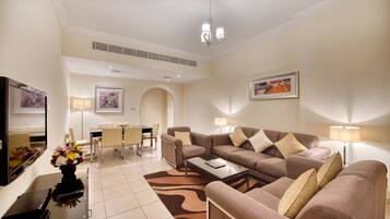 A modern living room with a sofa set, a coffee table, a TV, and a dining area with chairs and a table.