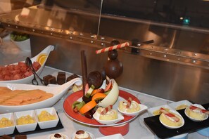 Ein reichhaltiges Buffet mit verschiedenen Speisen, darunter Früchte, Desserts und einer Schokoladenfontäne.
