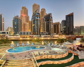A modern hotel with a large outdoor swimming pool, multiple levels of balconies, and a view of the city skyline. - Pearl Marina Hotel Apartments (Dubai)