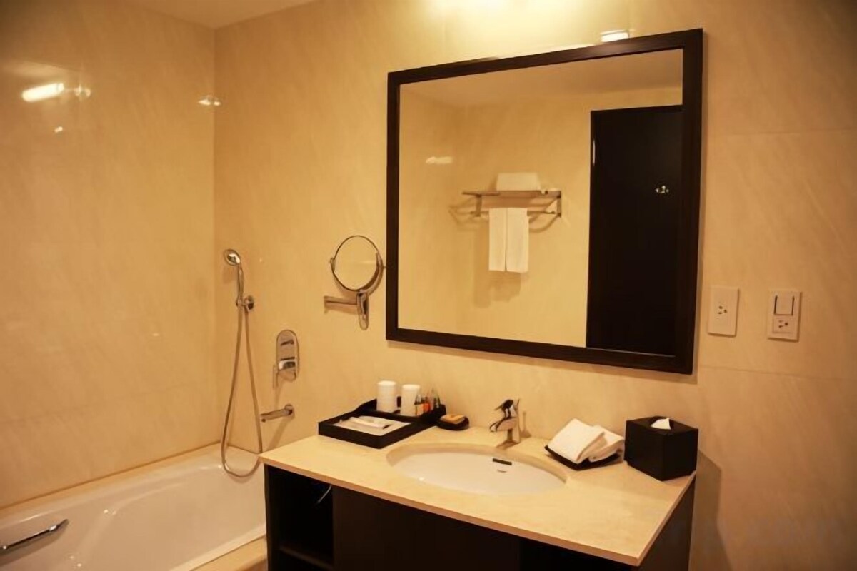 A bathroom with a bathtub, a sink, a mirror, and a towel rack.