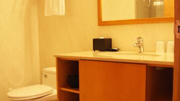 A bathroom with a toilet, sink, mirror, and towel rack.