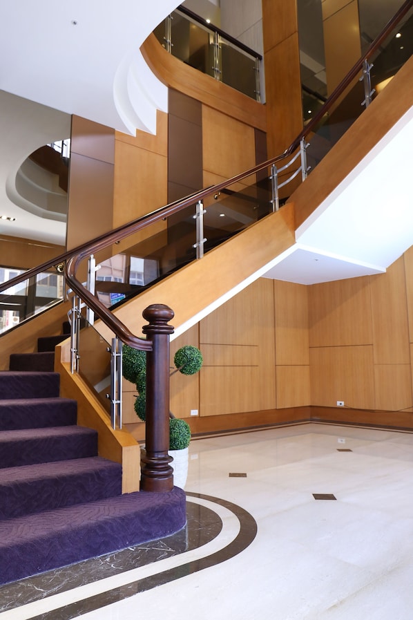 Un interior moderno con una escalera curva, paneles de madera y suelo de mármol.