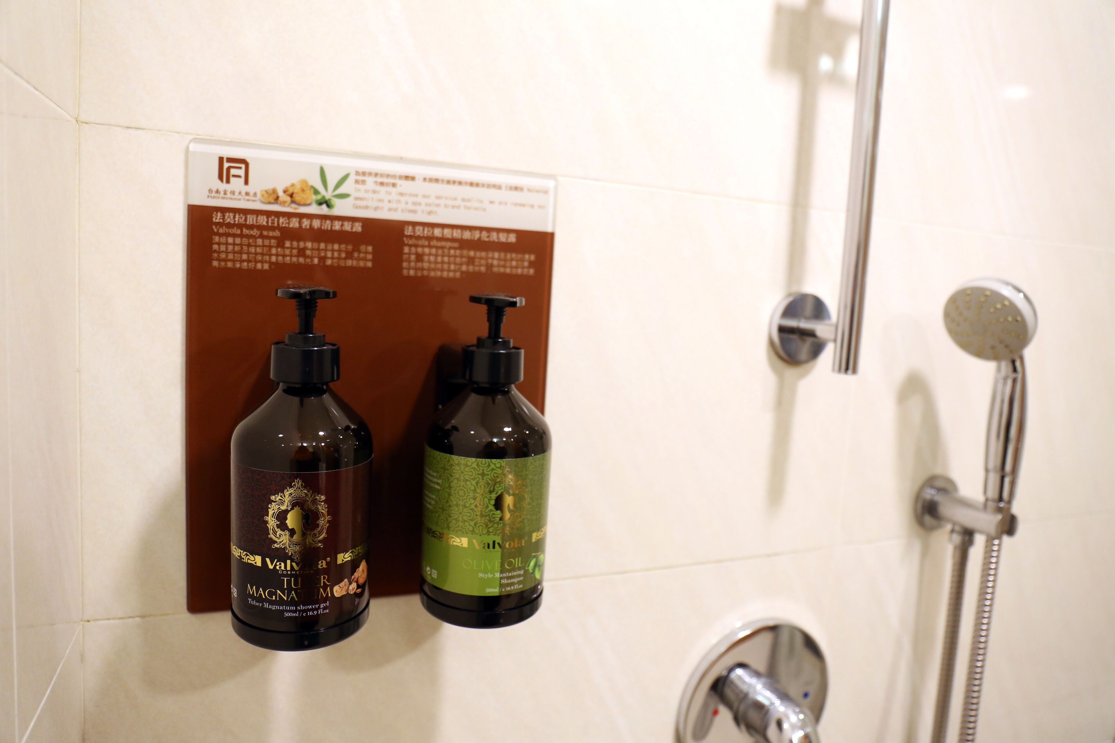 A bathroom with a shower, two bottles of Valvoline Magna Oil, and a sign with text in a foreign language.