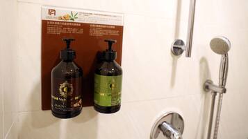 A bathroom with a shower, two bottles of Valvoline Magna Oil, and a sign with text in a foreign language.