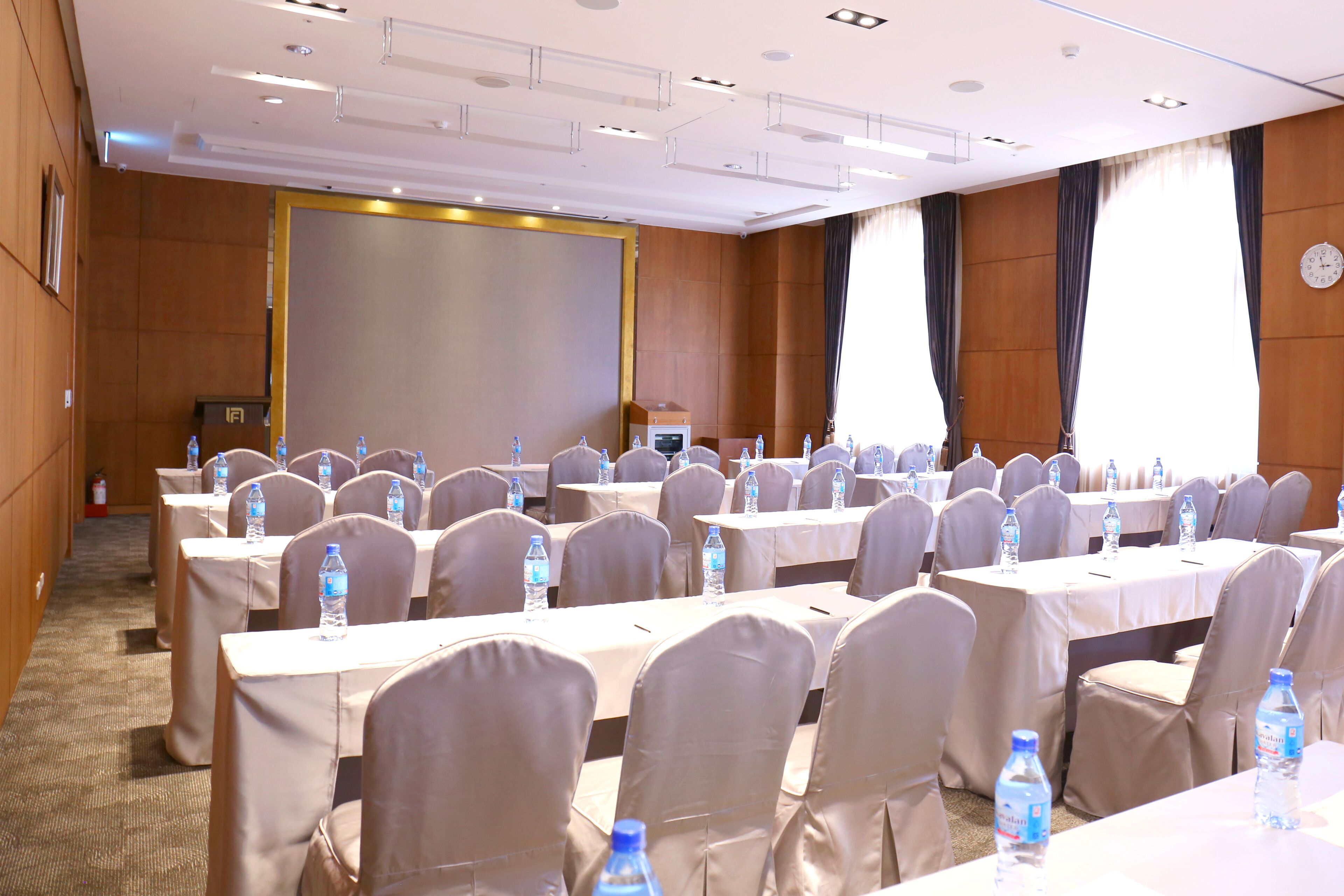 Un salón de conferencias con varias mesas, sillas y botellas de agua.