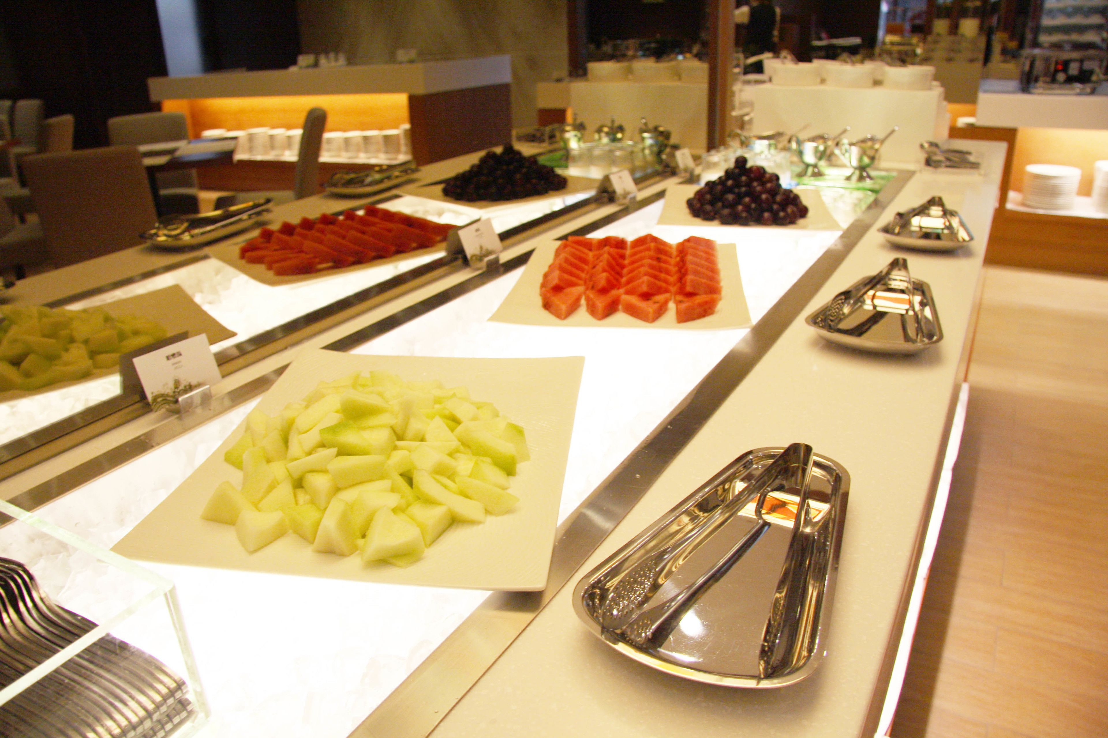 A buffet with various fruits and vegetables displayed in trays.