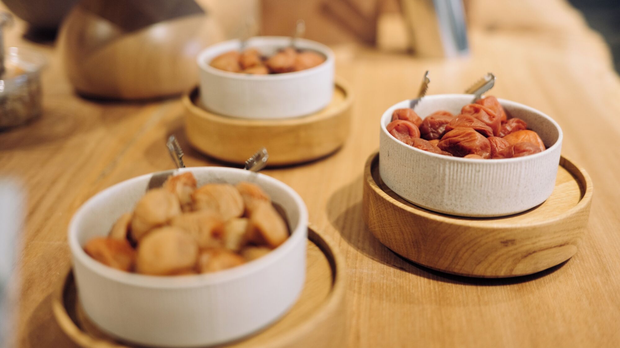 Three bowls of food on wooden coasters.