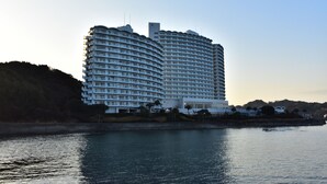 Un hotel grande y de varios pisos con fachada curva, ubicado junto al agua.