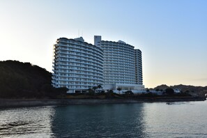 Ein großes, mehrstöckiges Hotel mit einer gewölbten Fassade, gelegen an einem Gewässer.