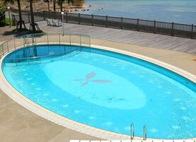 Una piscina azul cristalina con muelle de madera y barandilla de metal.