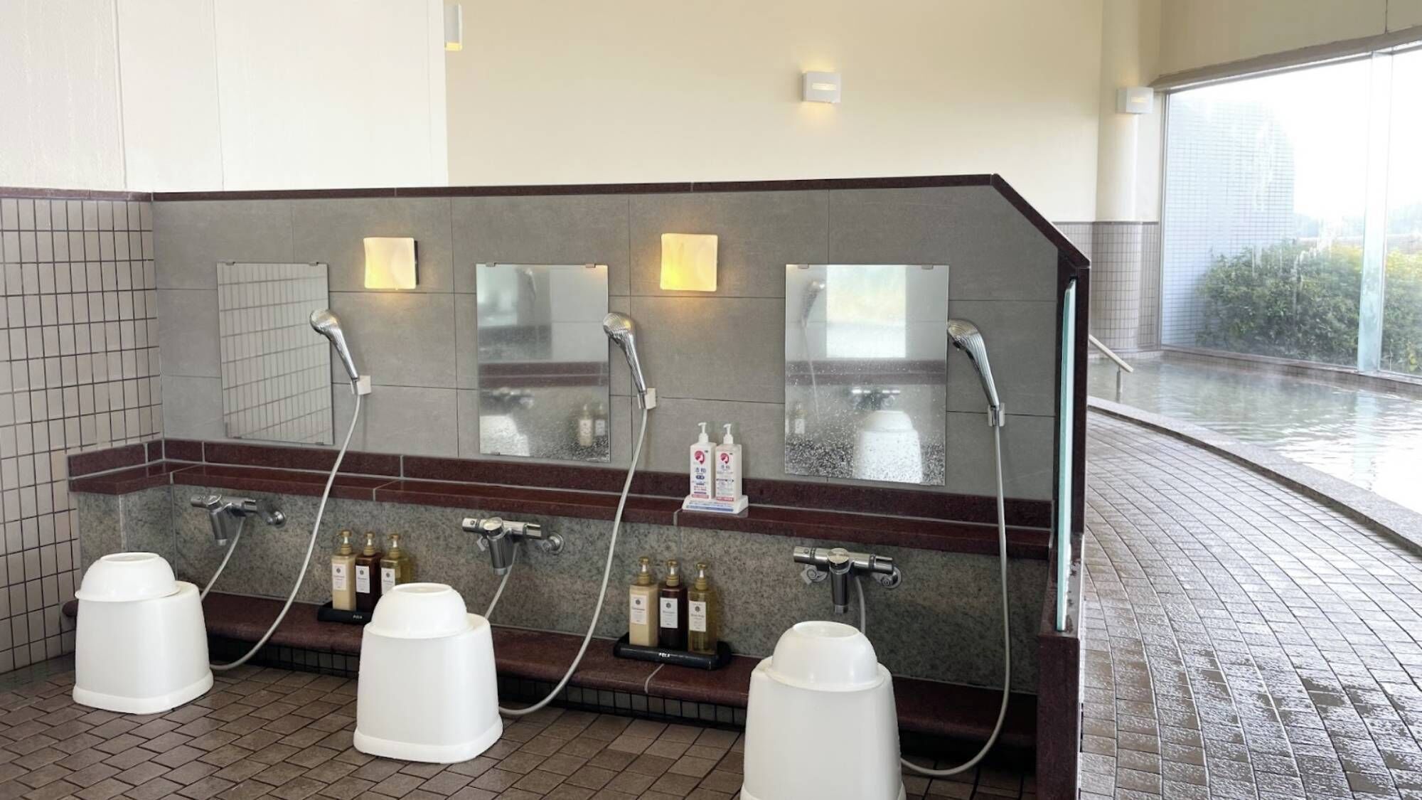Un bagno moderno con uno specchio grande, diversi lavabi e una zona doccia.