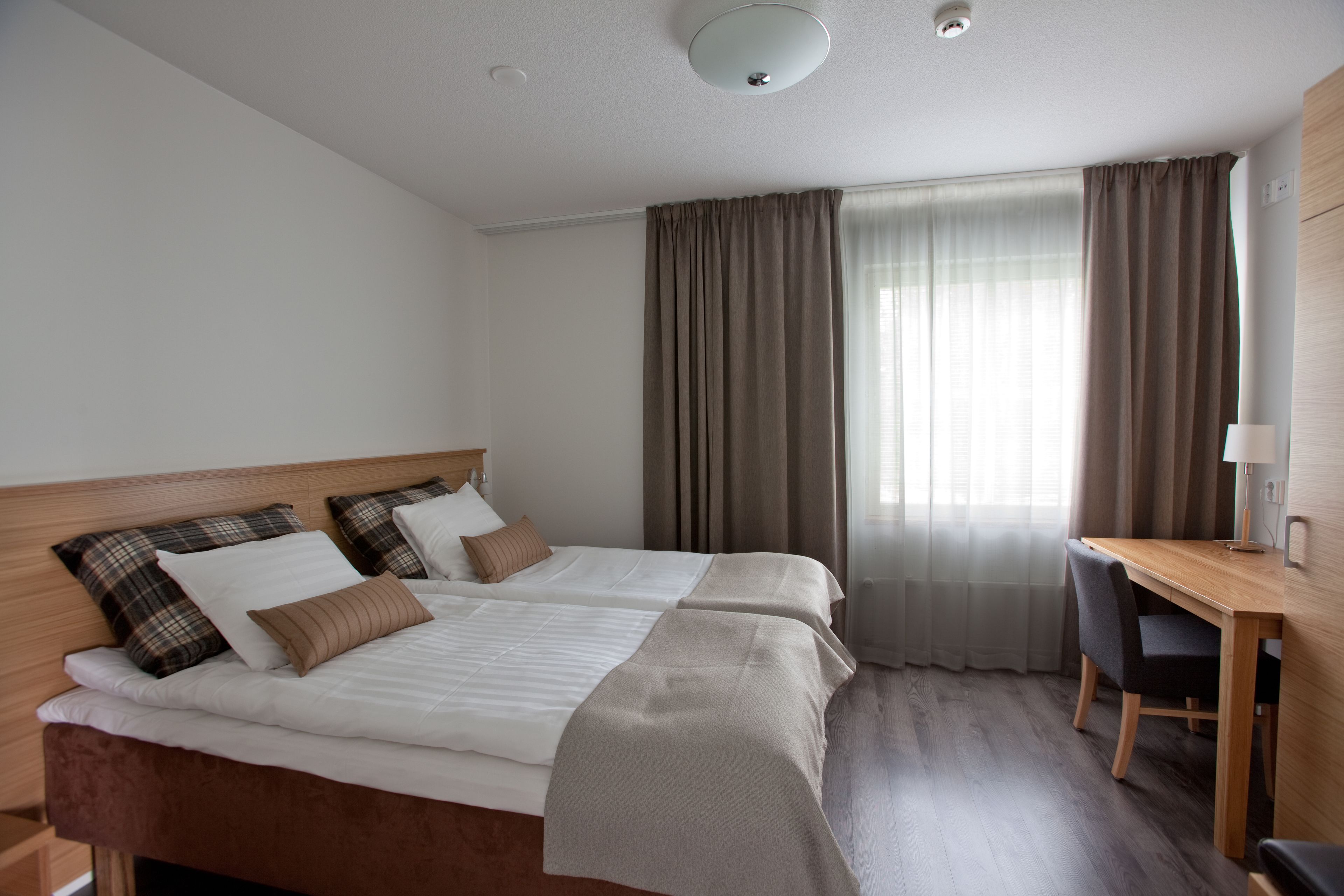 A hotel room with a double bed, a desk, and a chair.