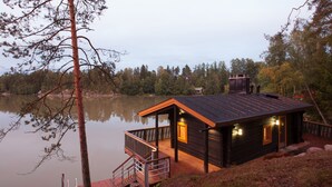 A cabin with a deck overlooking a calm lake, surrounded by trees. - Majatalo Onnela (Tuusula)
