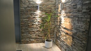 A corner with a stone wall, a potted plant, and a light fixture. - Majatalo Onnela (Tuusula)
