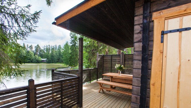 A wooden deck with a picnic table and benches overlooking a lake. - Majatalo Onnela (Tuusula)