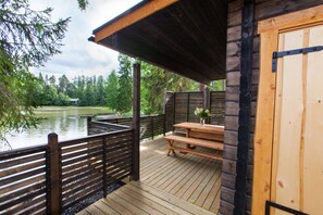 A wooden deck with a picnic table and benches overlooking a lake. - Majatalo Onnela (Tuusula)