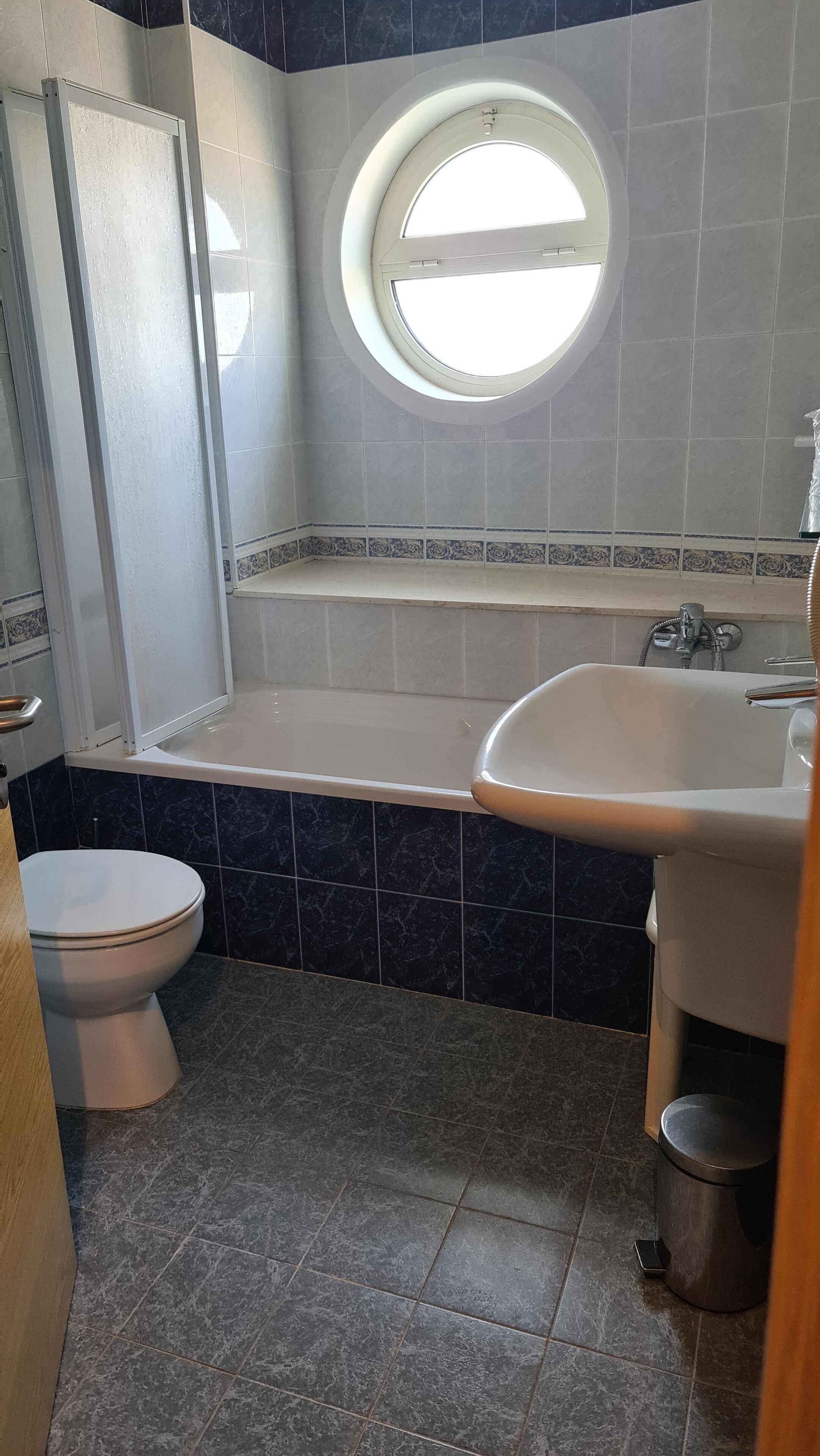 A bathroom with a bathtub, toilet, and a window.