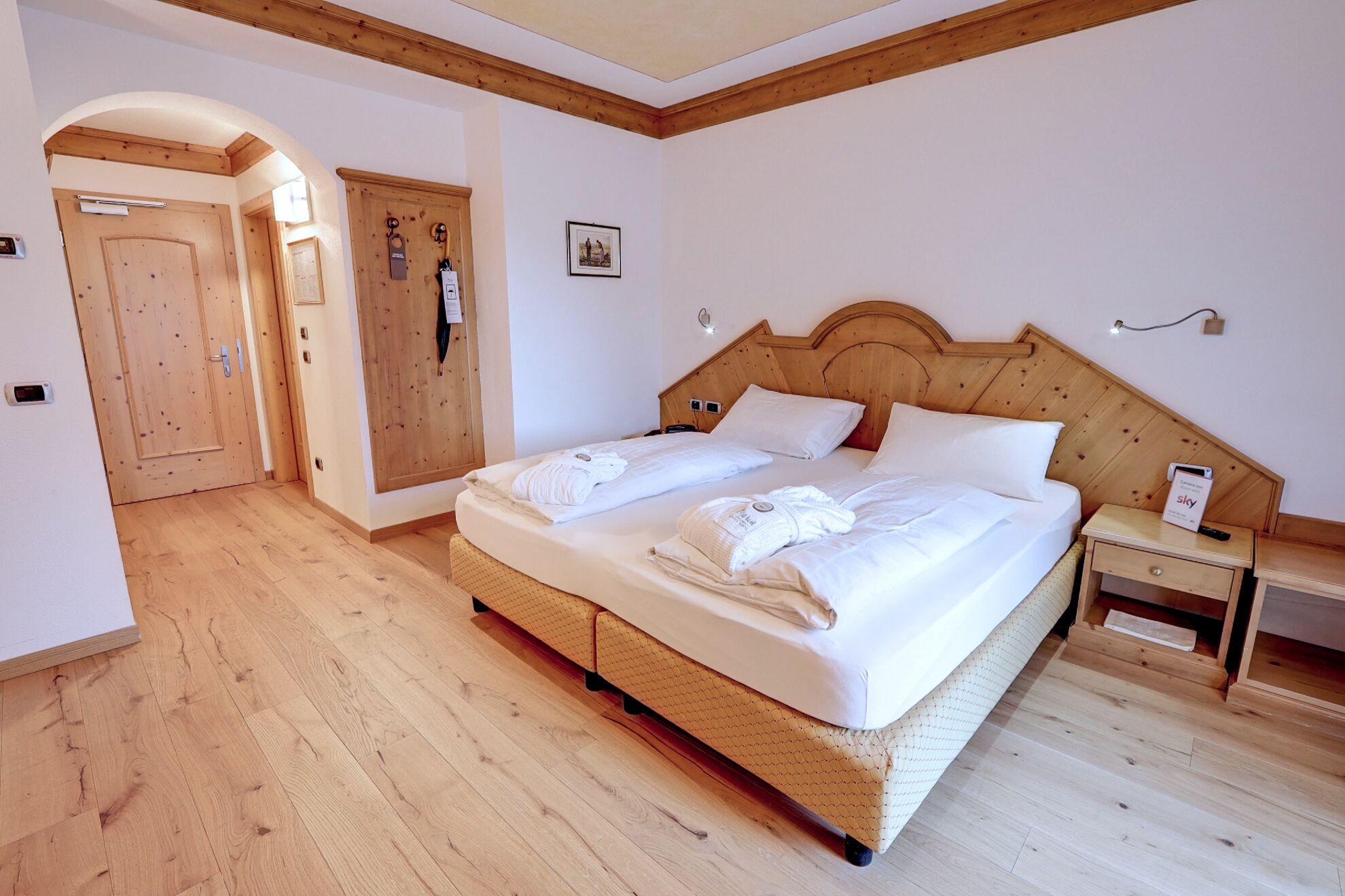 Ein Schlafzimmer mit einem hölzernen Bett, zwei Nachttischen, einem Beistelltisch und einer Holztür.