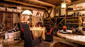 A rustic dining area with a wooden table set for two, surrounded by shelves of wine bottles and a variety of items. - Leading Relax Hotel Maria (Moena)