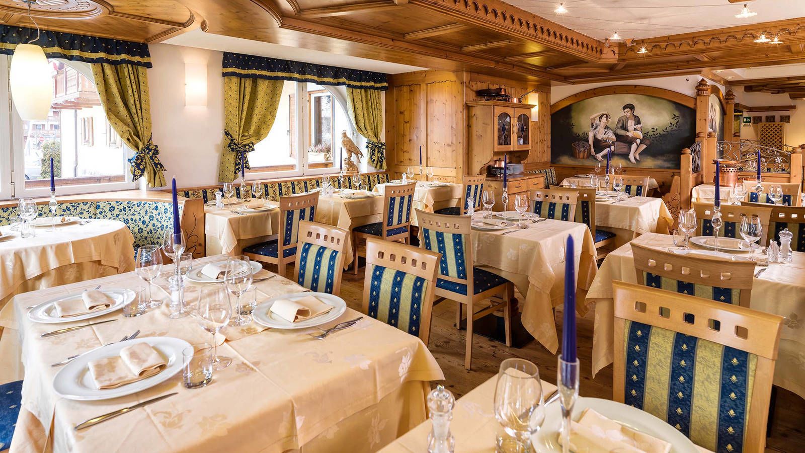 En restaurant med runde borde, blåstribede stole og et muralmaleri på væggen.