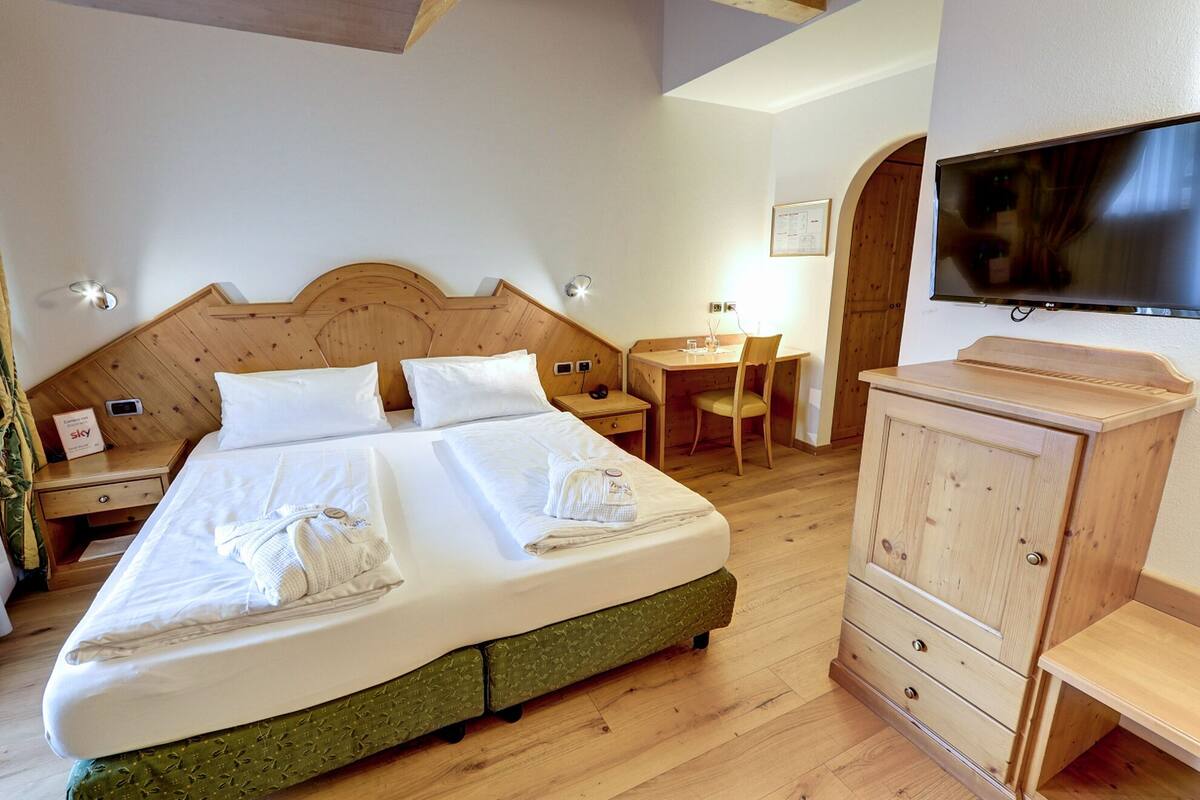 Una habitación de hotel con cama doble, escritorio, silla, televisor y armario.