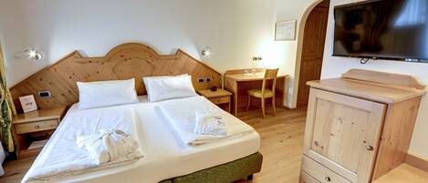 A hotel room with a double bed, a desk, a chair, a TV, and a wardrobe.