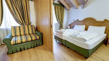 Een kamer met een bed, een bank, houten vloeren en een houten plafond.