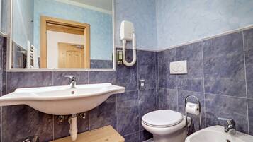 A bathroom with a large white sink, a toilet, and a bidet.