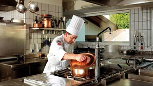 A chef in a professional kitchen with stainless steel appliances, copper cookware, and a clean, organized workspace. - Leading Relax Hotel Maria (Moena)