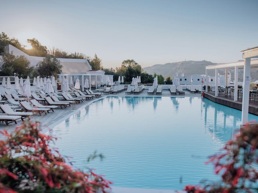 Una piscina techada, una piscina al aire libre, sombrillas