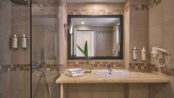 Une salle de bain avec une douche à parois de verre, un lavabo avec un miroir au-dessus et des articles de toilette posés sur le comptoir.