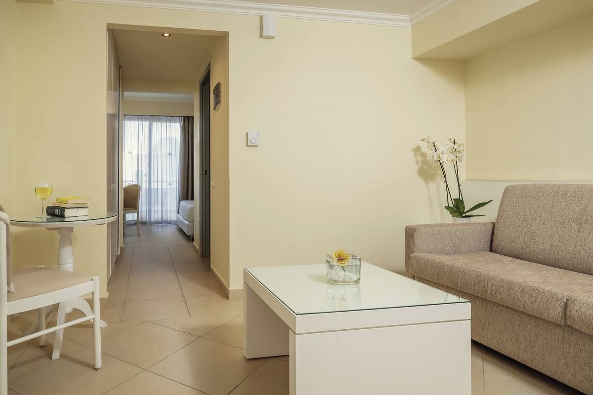 A modern living room with a sofa, a glass coffee table, and a dining area with a table and chair.