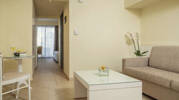 A modern living room with a sofa, a glass coffee table, and a dining area with a table and chair.