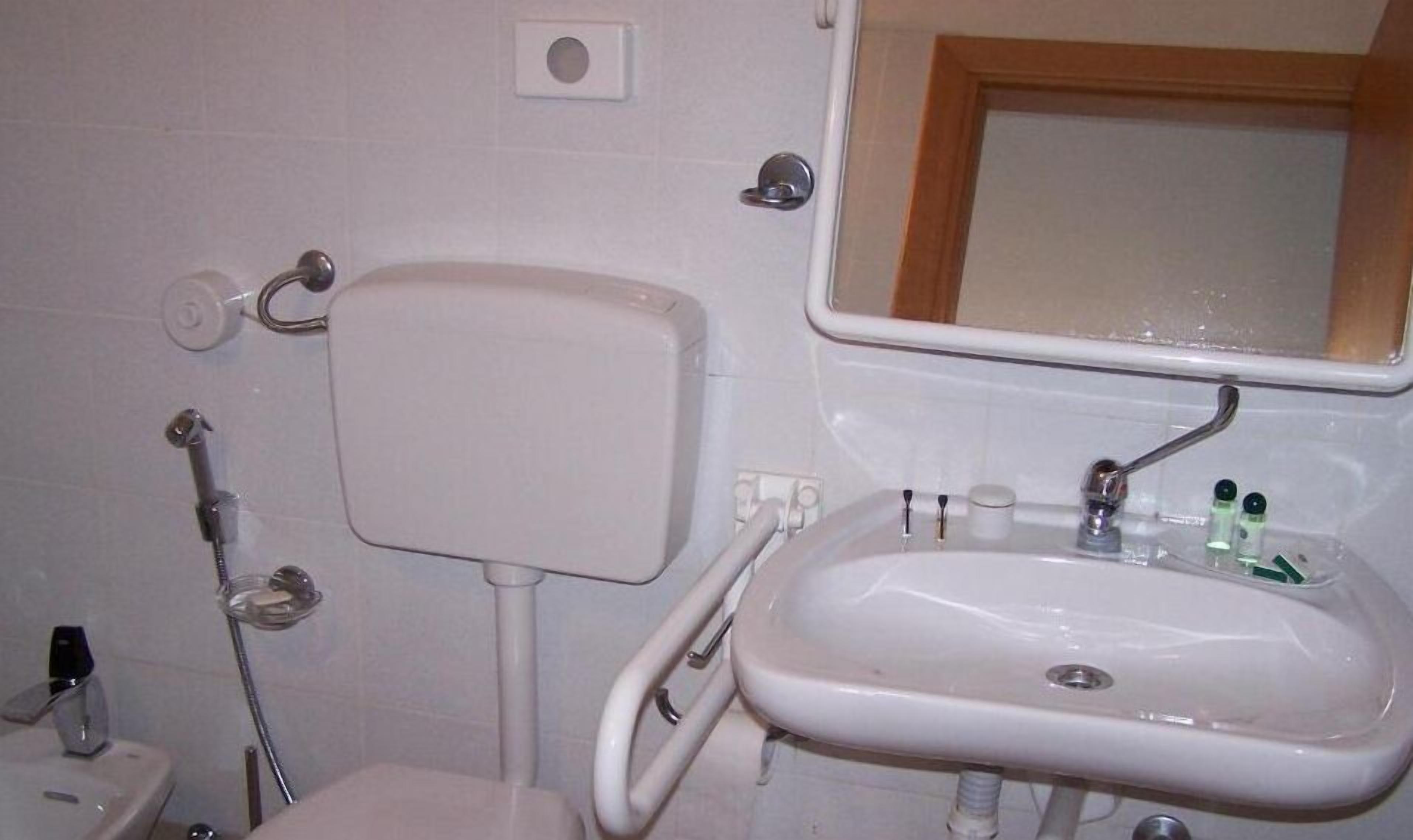 Een badkamer met toilet, wastafel en spiegel.
