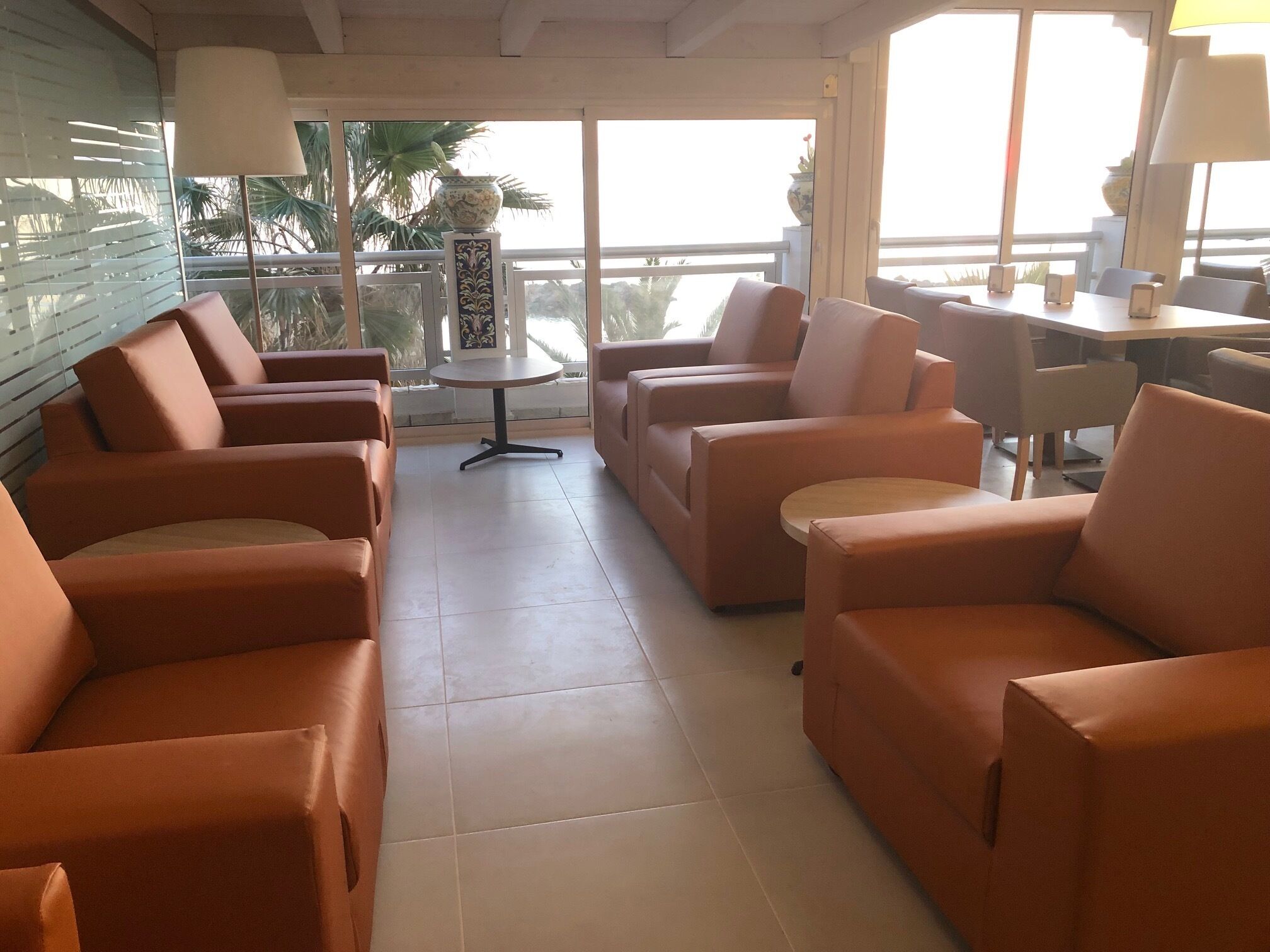 A spacious lounge area with orange sofas and a small round table.
