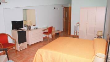 Un dormitorio con cama, escritorio, silla, televisor, cómoda y armario.