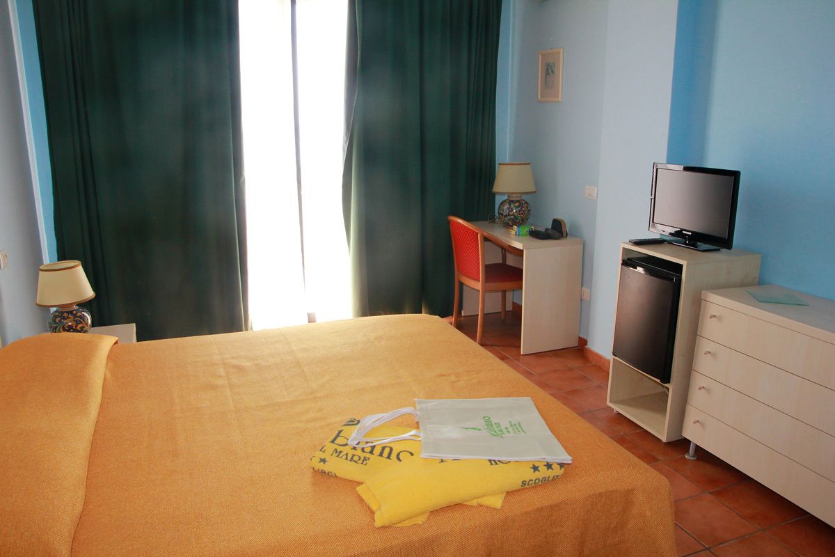 Une chambre d’hôtel comprenant un lit, un bureau avec une chaise, une télévision et une commode.