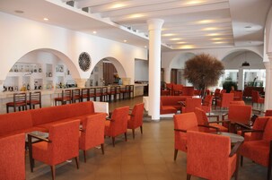 Amplio espacio interior con asientos rojos, columnas blancas y una zona de bar con estantes llenos de botellas.