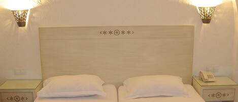 A double bed with white linens, two bedside tables with lamps, and a framed picture on the wall.