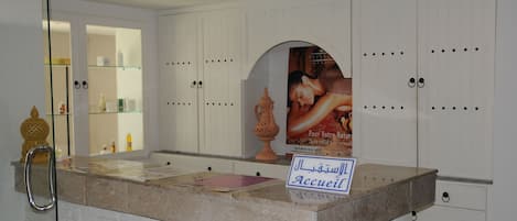 A reception area with a marble counter, a sign indicating the entrance, and a poster on the wall.