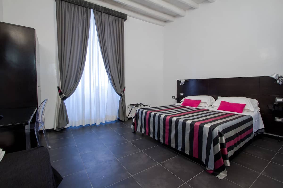 A hotel room with a bed, a desk, and a chair.