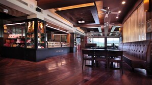 Ein Restaurant mit Holzboden, einer Theke mit einer Kühlvitrine und einer Sitzgelegenheit mit einer Bank und einem Tisch.