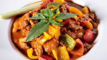 A bowl of stew with various vegetables and meat, garnished with a basil leaf.