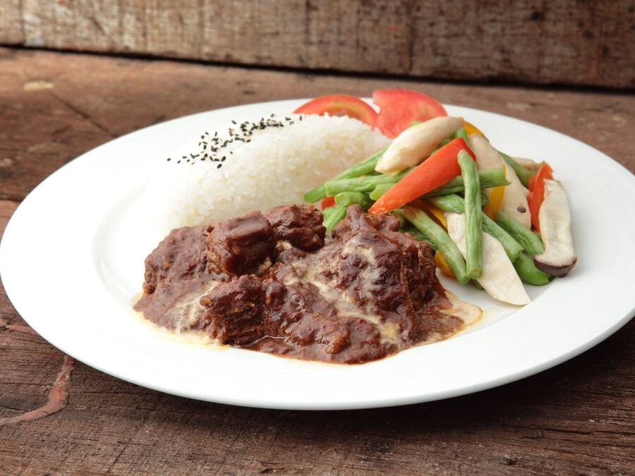 Une assiette de nourriture composée de riz, de viande et de légumes.