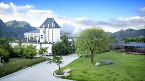 Ein modernes Gebäude mit einem zentralen Turm, umgeben von einem gepflegten Rasen und Bäumen.
