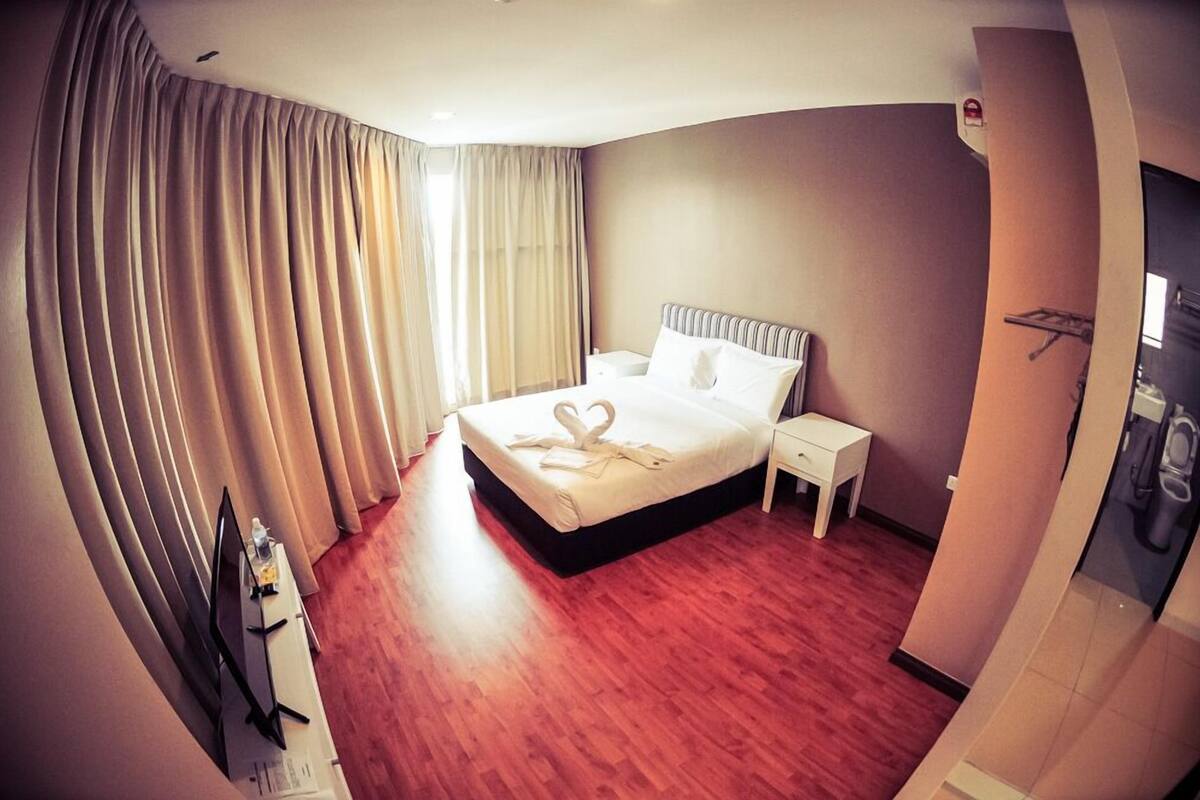A hotel room with a bed, bedside table, and curtains.