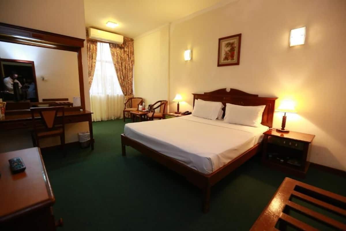 Una habitación de hotel con una cama grande, un escritorio, una silla y una mesita.