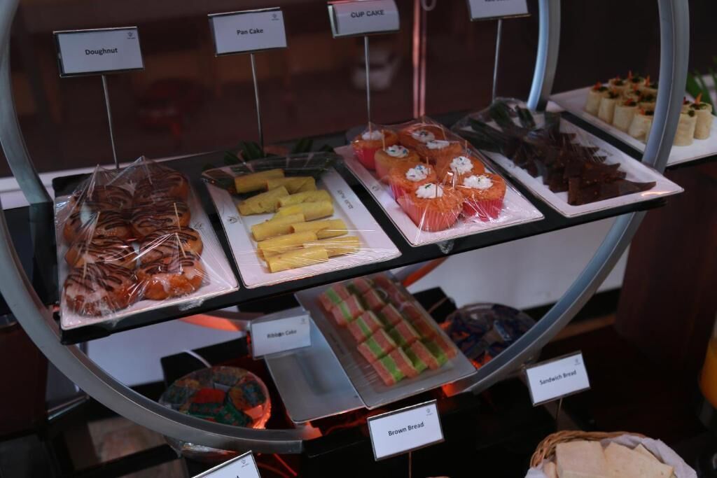 A display case with various baked goods including doughnuts, pan cakes, and sandwiches.